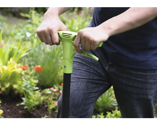 Personne utilisant un désherbeur dans le jardin.