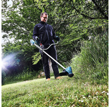 Un homme utilise un coupe-bordure à batterie dans le jardin.