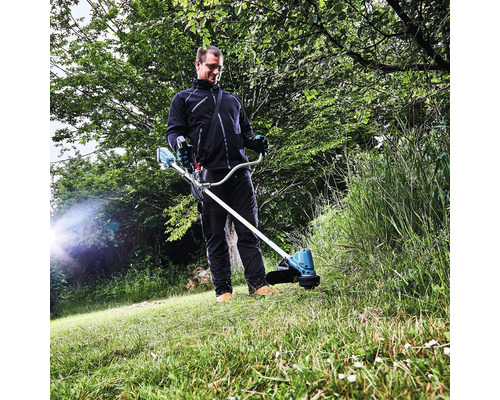 Un homme utilise un coupe-bordure à batterie dans le jardin.