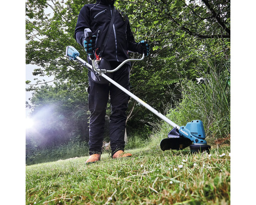 Une personne utilise un coupe-bordures à batterie Makita dans le jardin.