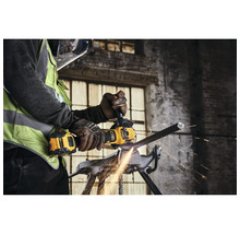 Mann schneidet mit einem Winkelschleifer ein Metallstück in einem Schraubstock. Funken fliegen.