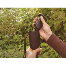 Person setzt Akku in ein Gartengerät ein.