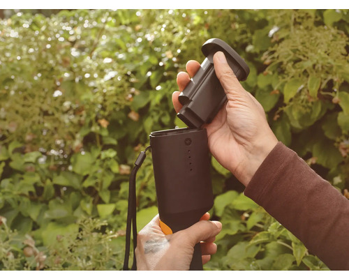 Person setzt Akku in ein Gartengerät ein.