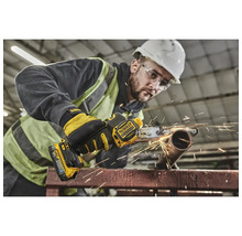 Ein Arbeiter verwendet einen Bandschleifer, um ein Metallrohr zu bearbeiten, wobei Funken entstehen.