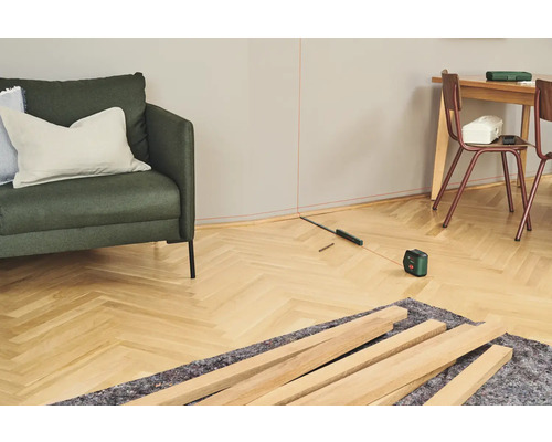 Vue d'une pièce avec un laser de nivellement, des lattes de bois et des meubles pour des travaux de rénovation