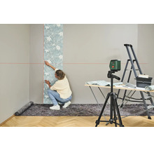 Femme tapissant un mur avec un niveau à bulle, une échelle et une table à tapisser
