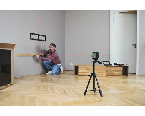 Un homme installe un support TV avec un laser lignes croisées