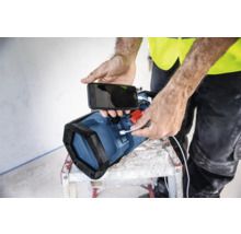 Une personne recharge un téléphone portable avec une lampe de travail.