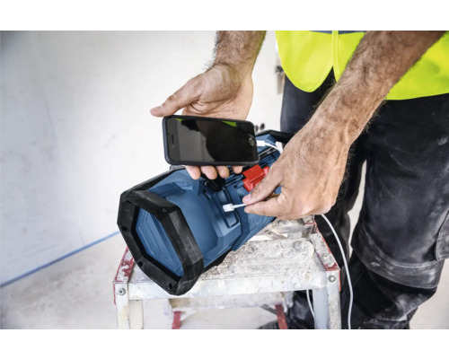 Une personne recharge un téléphone portable avec une lampe de travail.