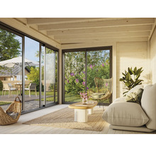 Heller Raum mit Sofa, Korbstuhl und Blick durch große Fenster auf Terrasse und Garten