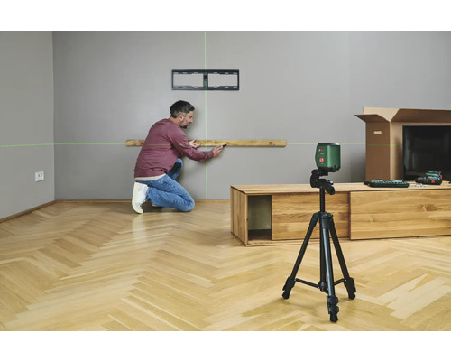 Un homme utilise un laser lignes croisées pour aligner un niveau à bulle sur un mur