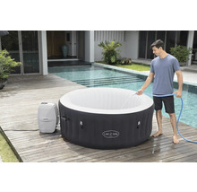 Jacuzzi Lay-Z-Spa gonflable avec un homme le remplissant avec un tuyau, sur une terrasse en bois