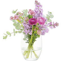 Bouquet de fleurs avec des renoncules et du lilas dans un vase en verre