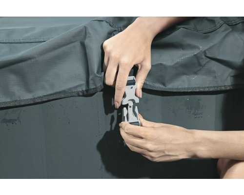 Une personne fixe une fermeture à clip sur une housse de protection.