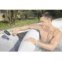 Un homme utilise un panneau de commande de bain à remous gonflable à l'extérieur