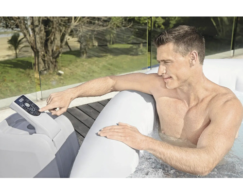 Un homme utilise un panneau de commande de bain à remous gonflable à l'extérieur