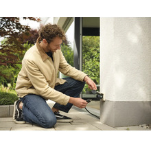 Mann schliesst Aussensteckdose an Hauswand an