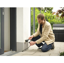 Mann schliesst Stecker an Aussensteckdose an