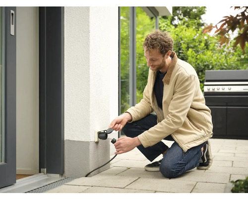 Mann schliesst Stecker an Aussensteckdose an