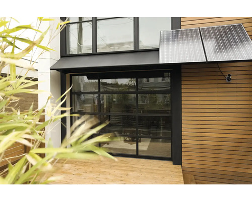 Außenansicht eines Hauses mit Solarpanelen und Glasgaragentor