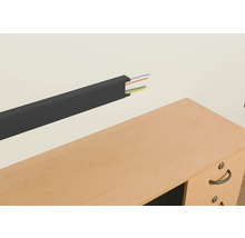 Goulotte de câbles en plastique avec câbles sur un mur au-dessus d'un bureau