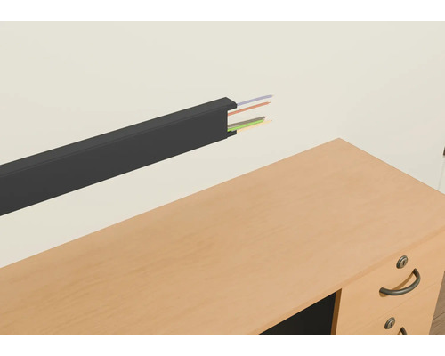 Goulotte de câbles en plastique avec câbles sur un mur au-dessus d'un bureau