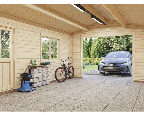 Vue intérieure d'un garage avec murs en bois, établi, aspirateur, vélo et une voiture garée à l'extérieur.