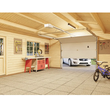 Garage en bois avec établi, mur à outils et porte de garage partiellement ouverte