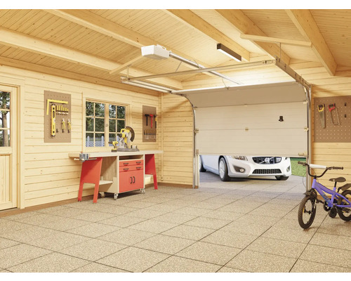 Garage en bois avec établi, mur à outils et porte de garage partiellement ouverte
