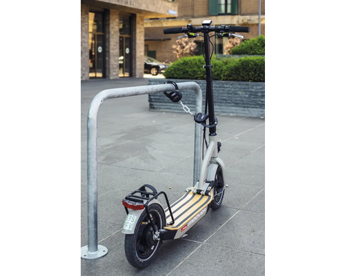 Une trottinette électrique est fixée à un range-vélos avec un cadenas à combinaison.