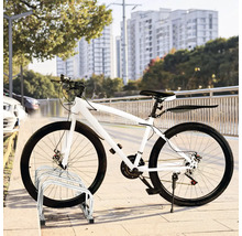 Vélo blanc garé sur un range-vélos devant un paysage urbain.