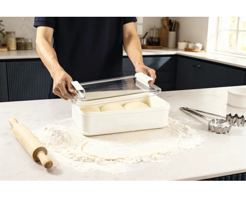 Szene in einer Küche: Ein Mann öffnet eine Frischhaltebox mit Teiglingen, umgeben von Mehl, einem Nudelholz und Ausstechformen.