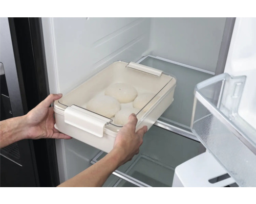 Person stellt eine Teigschüssel mit Deckel in den Kühlschrank