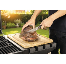Préparation de viande sur un barbecue avec planche à découper et couteau.