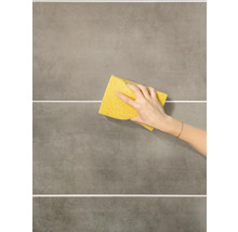 Hand wischt mit einem Schwamm über Fliesen.