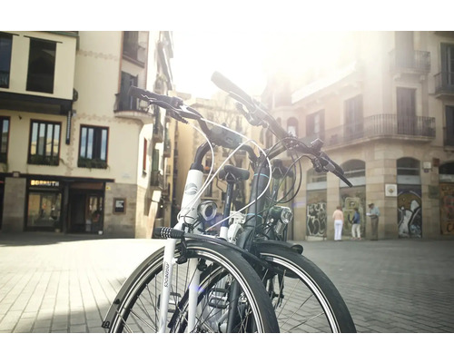 Deux vélos sont garés dans un environnement urbain devant des bâtiments.
