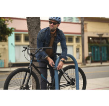 Un homme attache son vélo à un range-vélos avec un antivol à code