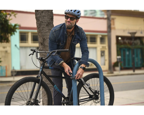 Un homme attache son vélo à un range-vélos avec un antivol à code