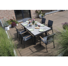 Une table à manger avec des chaises sur une terrasse, dressée avec des assiettes et des couverts.