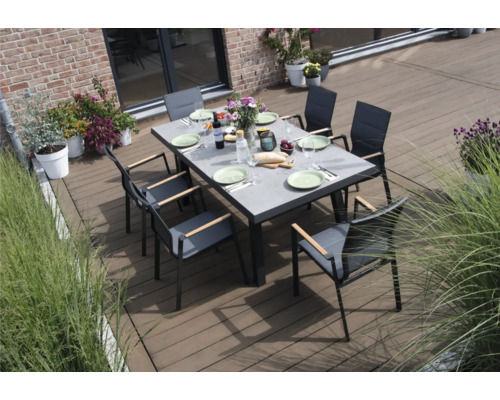Une table à manger avec des chaises sur une terrasse, dressée avec des assiettes et des couverts.