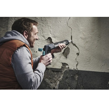 Mann, der eine Rissfüllpistole von Wolfcraft verwendet, um einen Riss in einer Wand zu füllen.