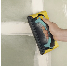 Ponceuse manuelle utilisée pour poncer un mur.