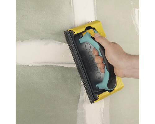 Ponceuse manuelle utilisée pour poncer un mur.