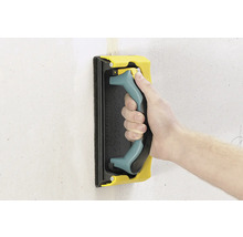 Main avec hérisson abrasif pour poncer un mur