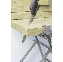 Dämmstoff wird mit einem Messer auf einer Werkbank zugeschnitten.