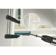 Eine Bohrmaschine bohrt ein Loch mit Hilfe einer Bohrlehre in ein Regal.