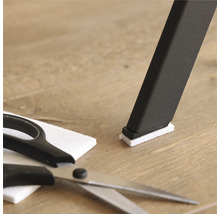 Pied de chaise avec patin en feutre, patin en feutre et ciseaux sur plancher en bois