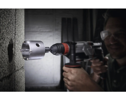 Mann bohrt mit einer Bohrmaschine ein Loch in eine Wand.