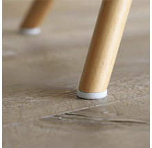 Detailansicht eines Stuhlbeins mit Bodenschoner auf einem Holzboden.