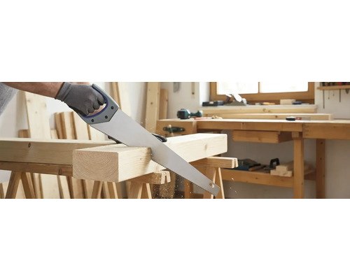 Une scie à main coupe un morceau de bois sur un établi.